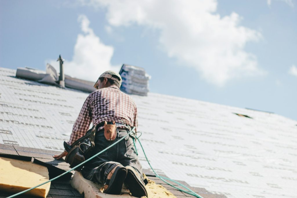 Roofer carefully installing shingles on a residential roof